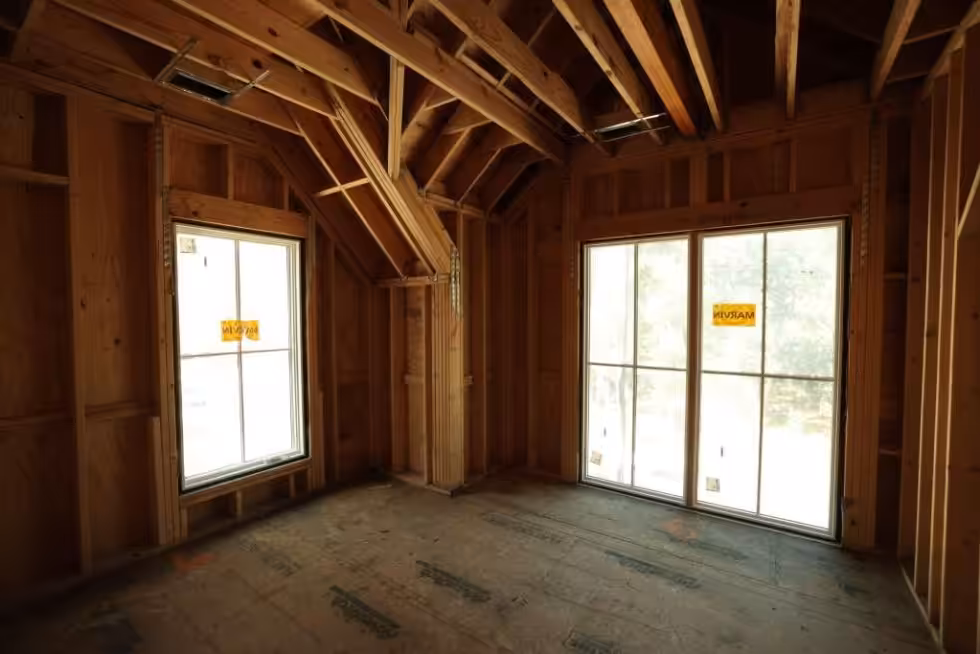 Sloped roof framing over a top-floor room with two windows, photographed before insulation and drywall