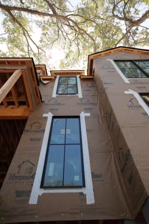 What Is a Change Order in Construction? How It Works on a Home Build Wall wrapped in HydroGap weather barrier with a tall window set and trimmed in white, under the eaves of a new home